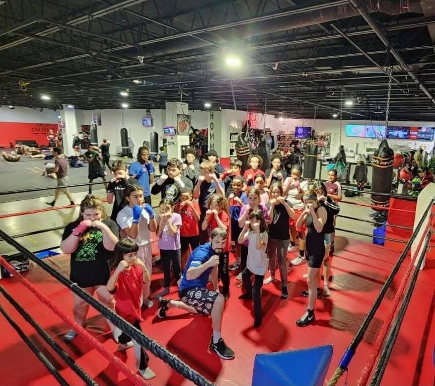 Un groupe de jeunes en position de garde dans le ring du Club de boxe Paradis
